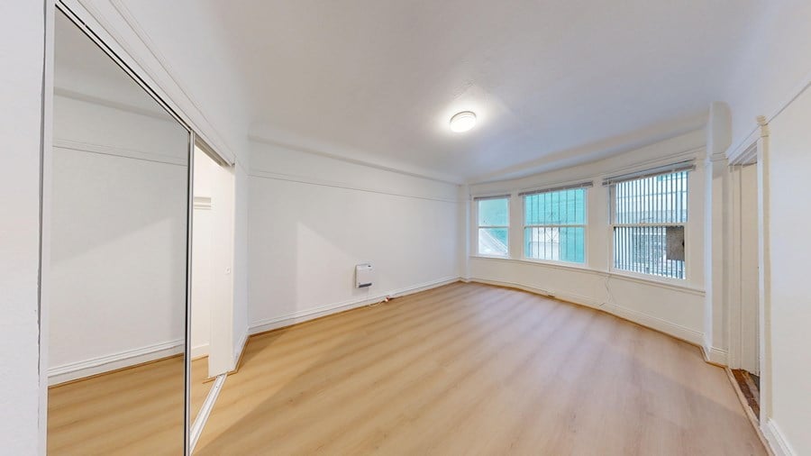 A room with wooden floors and a window with blinds.